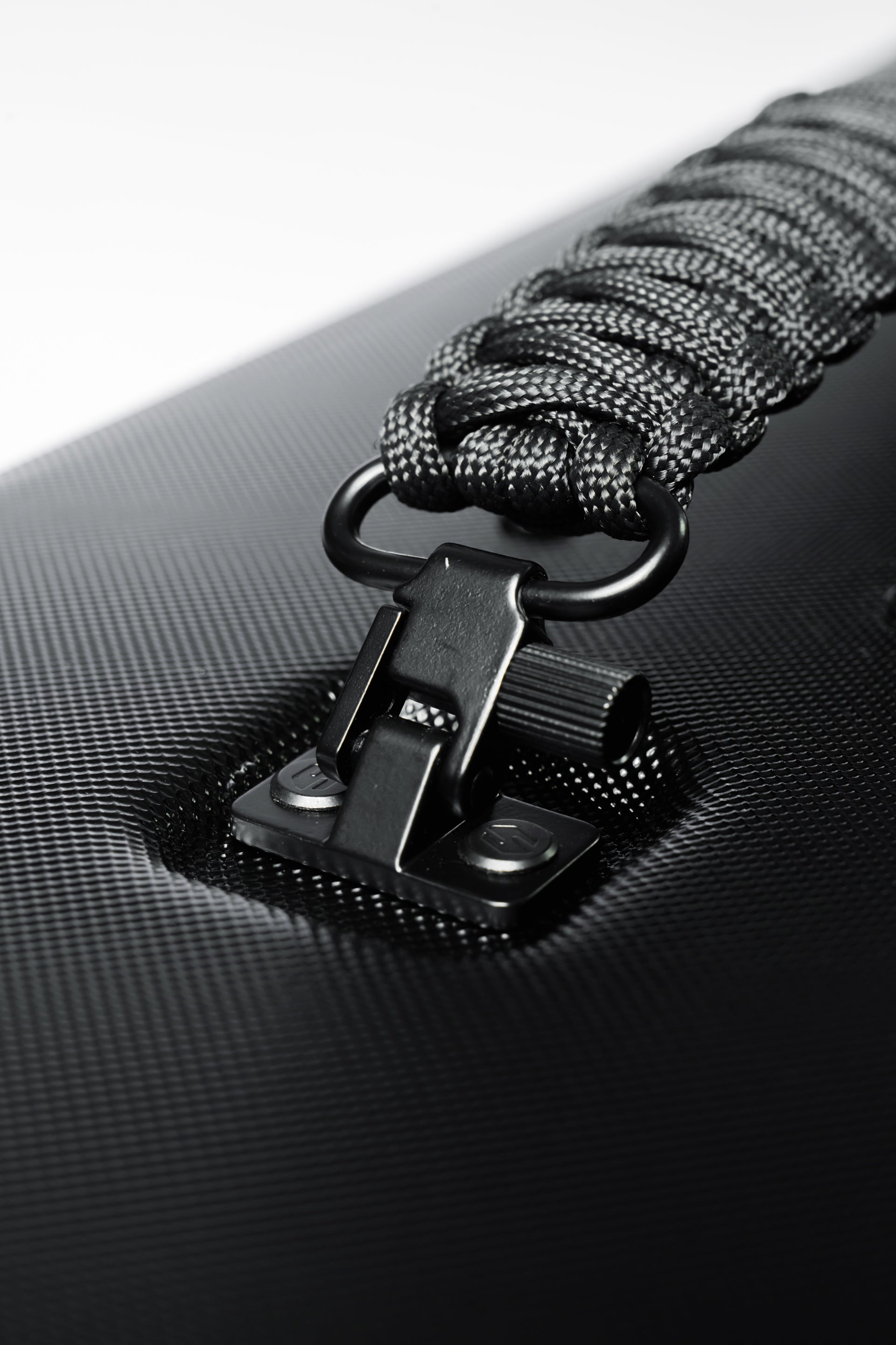 Close-up of Shinogi Paracord Utility Handle matte black zinc alloy connector clip attached to Case 15-25 ABS textured surface