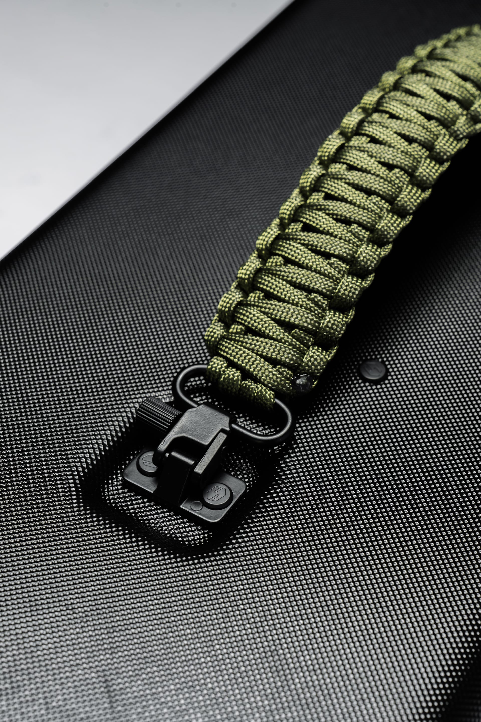 Shinogi Paracord Utility Handle olive green colorway, close-up of matte black connector clip and hand-woven paracord weave on Case 15-25