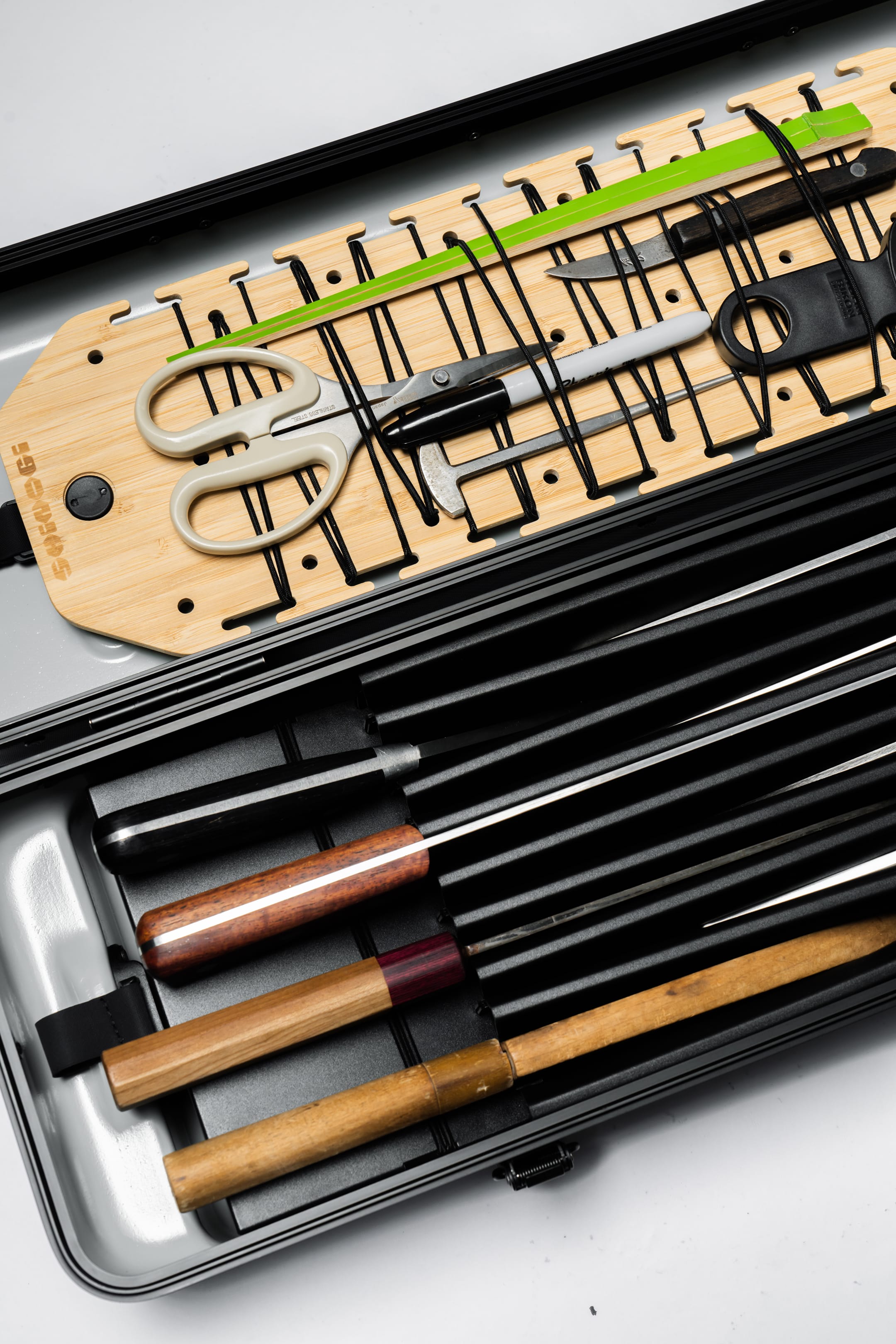 Shinogi Case 15-25 interior close-up showing bamboo splint lid organizer with elastic cords securing kitchen scissors and tools, and accordion dividers holding chef knives with wooden handles