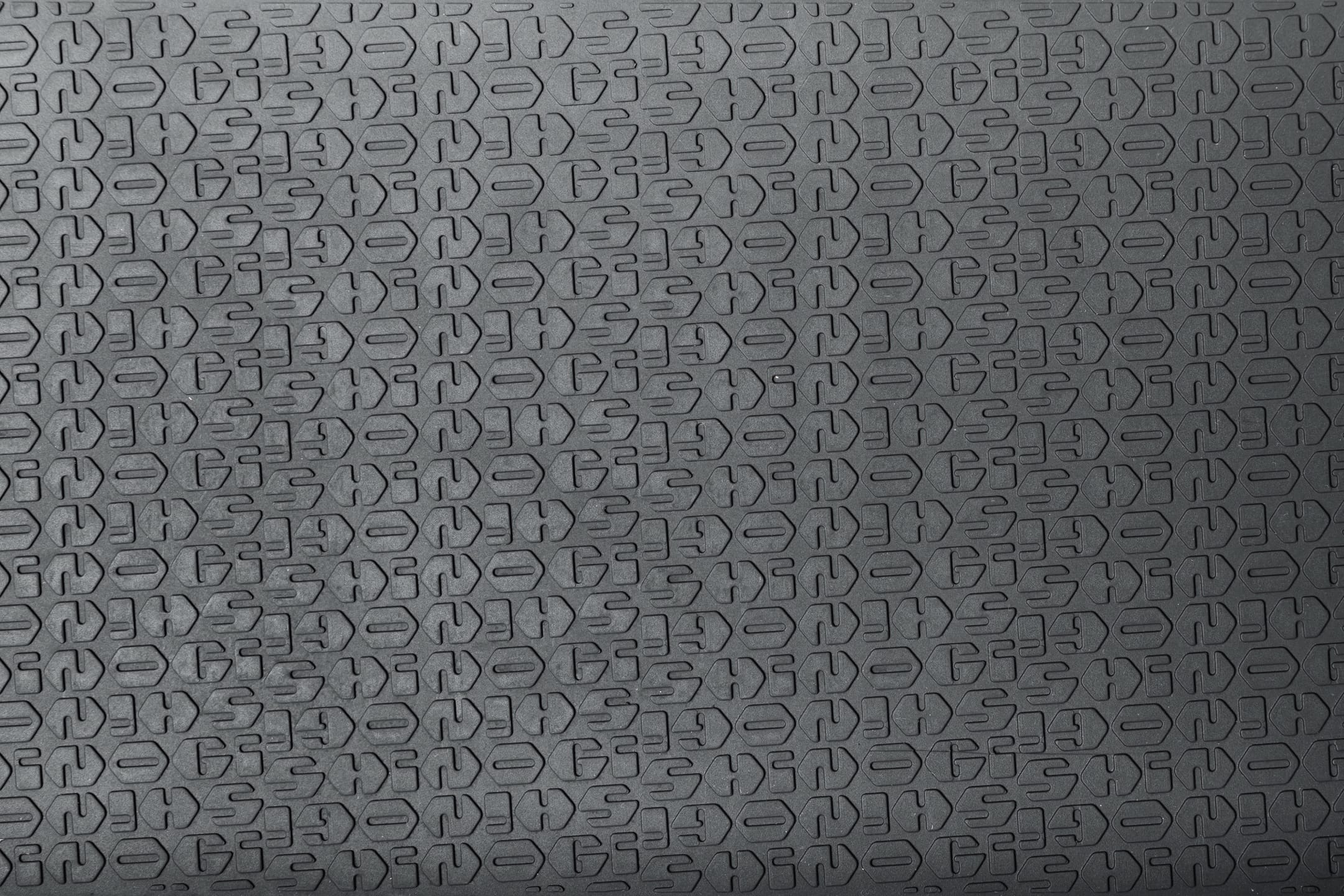 Close-up of Shinogi Monogram Silicone Pad embossed texture pattern, showing repeating Shinogi logo motif pressed into food-safe black silicone for non-slip grip